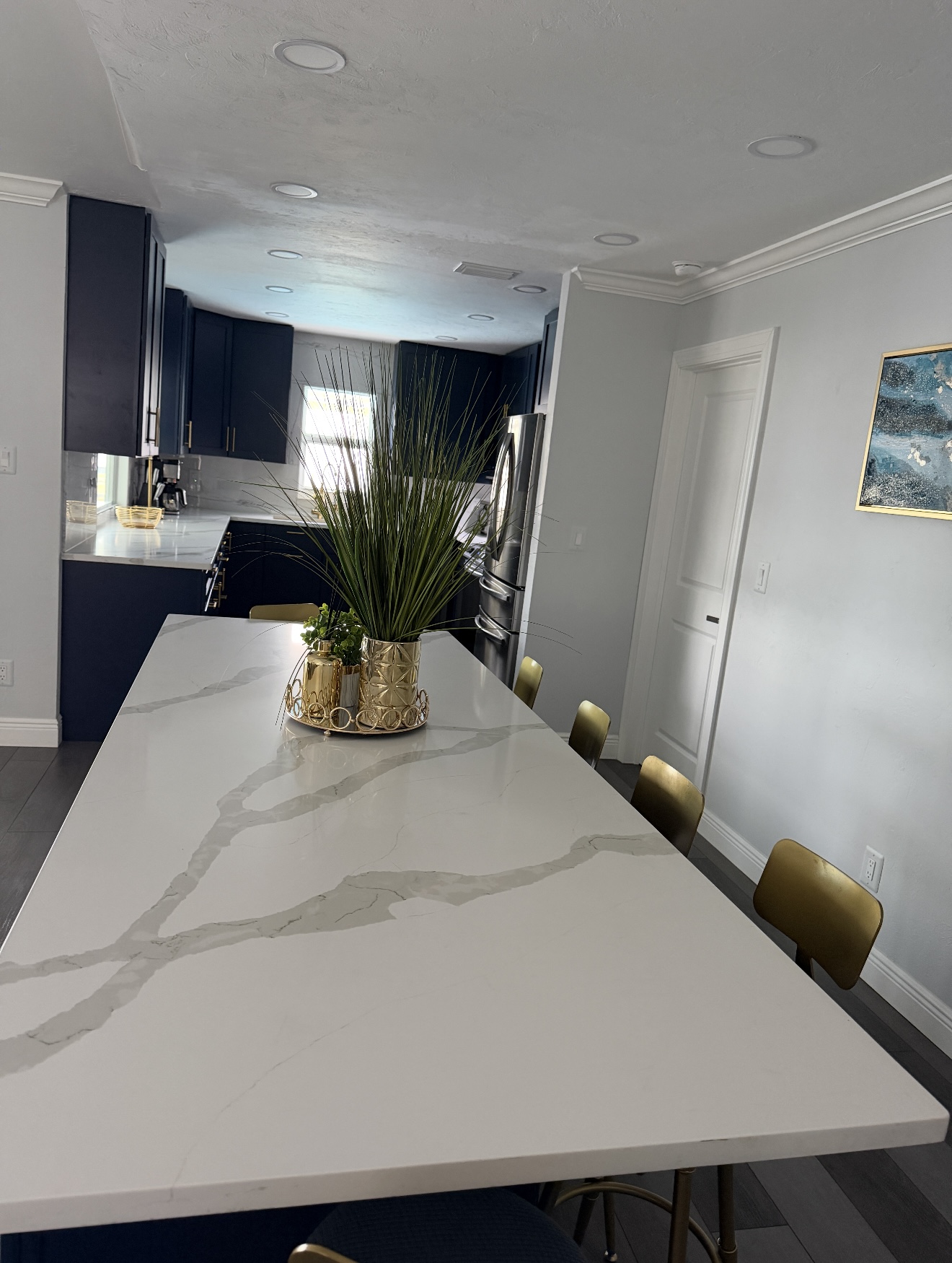 A clean white kitchen island with navy cabinets and gold accents