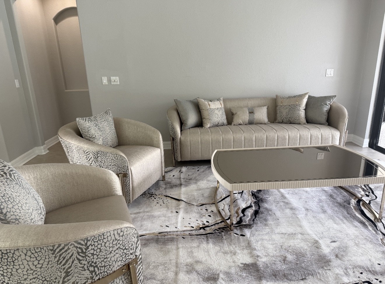 A tidy living room with cream seating and a reflective coffee table
